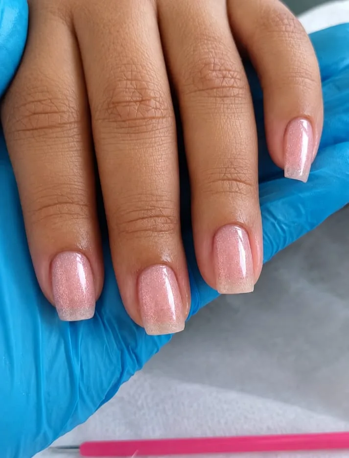 Mão com unhas naturais curtas em rosa nude com brilho